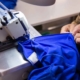 Clemens Uniform crafts a blue work uniform using an industrial sewing machine as part of its commercial uniform program.