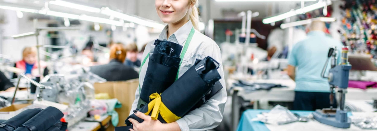 Clemens Uniform team member sewing a blue work uniform on an industrial machine for a managed manufacturing uniform program.