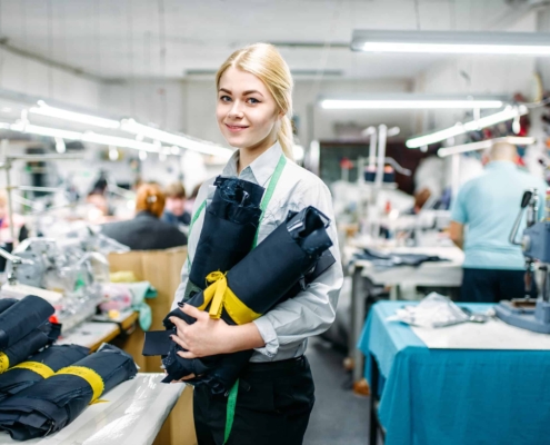 Clemens Uniform team member sewing a blue work uniform on an industrial machine for a managed manufacturing uniform program.