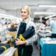 Clemens Uniform team member sewing a blue work uniform on an industrial machine for a managed manufacturing uniform program.